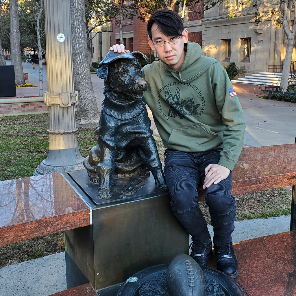 Adam Parkzer sitting next to a dog statue