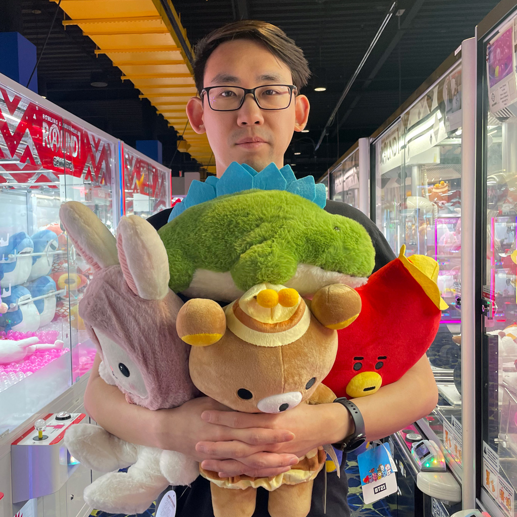 Adam Parkzer holding four large plushies at an arcade